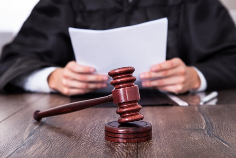 Close-up Of Male Judge In Front Of Mallet Holding Documents