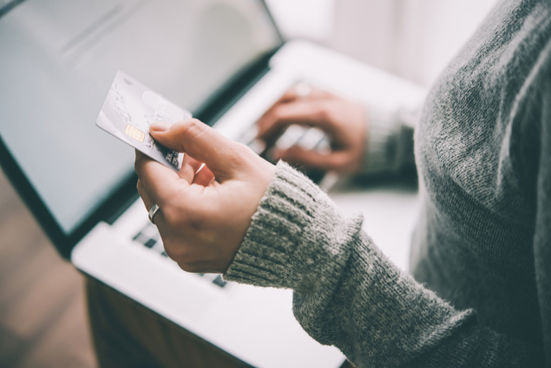 Hands holding plastic credit card and using laptop