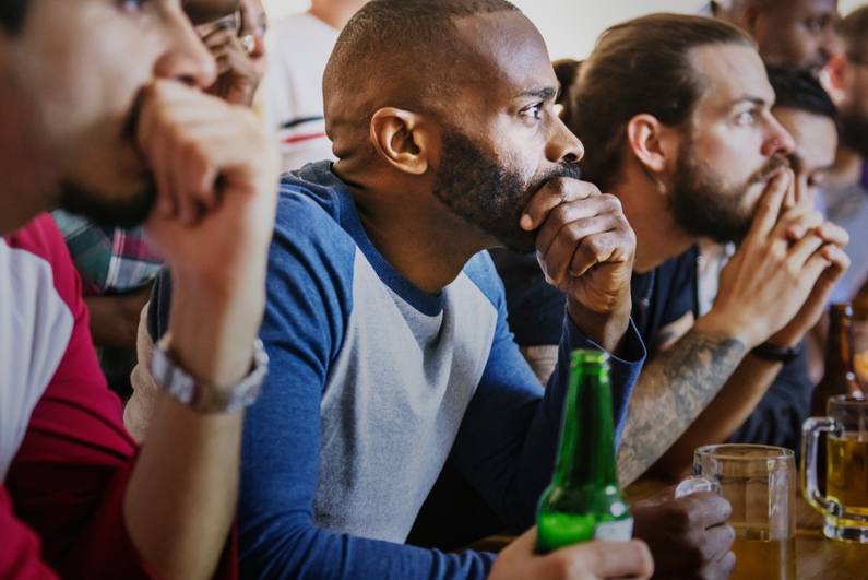 Friends watching sports on TV at bar