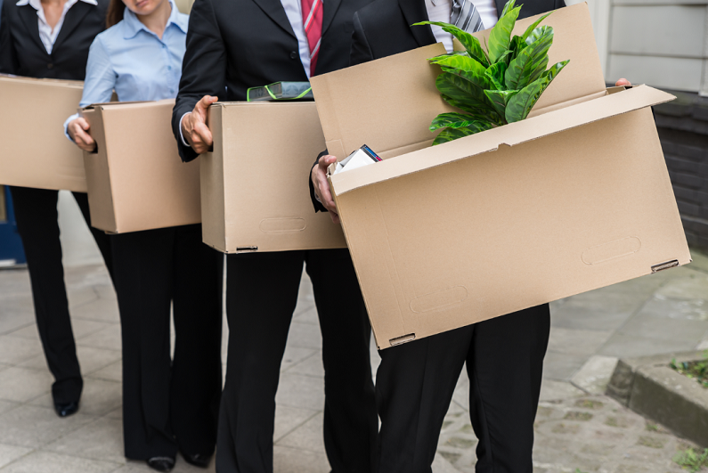 Line of office workers holding boxes of personal items.