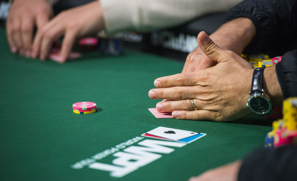 poker players' hands with chips on table with WPT logo