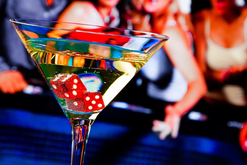 red dice in the cocktail glass in front of casino gambling table