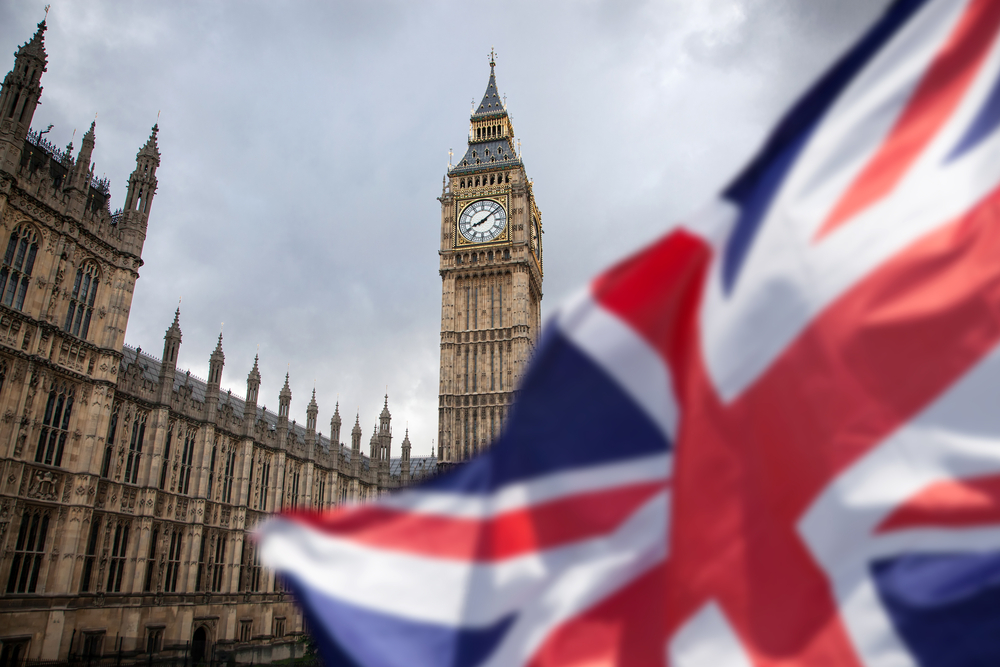 Big Ben Clock Tower and Houses of Parliament in London with Union Jack flag in foreground