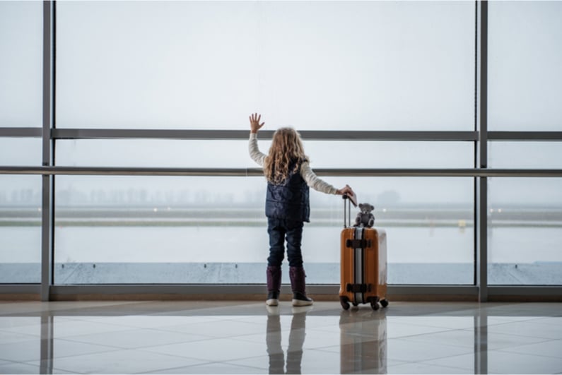 Child waving goodbye to plane at airport