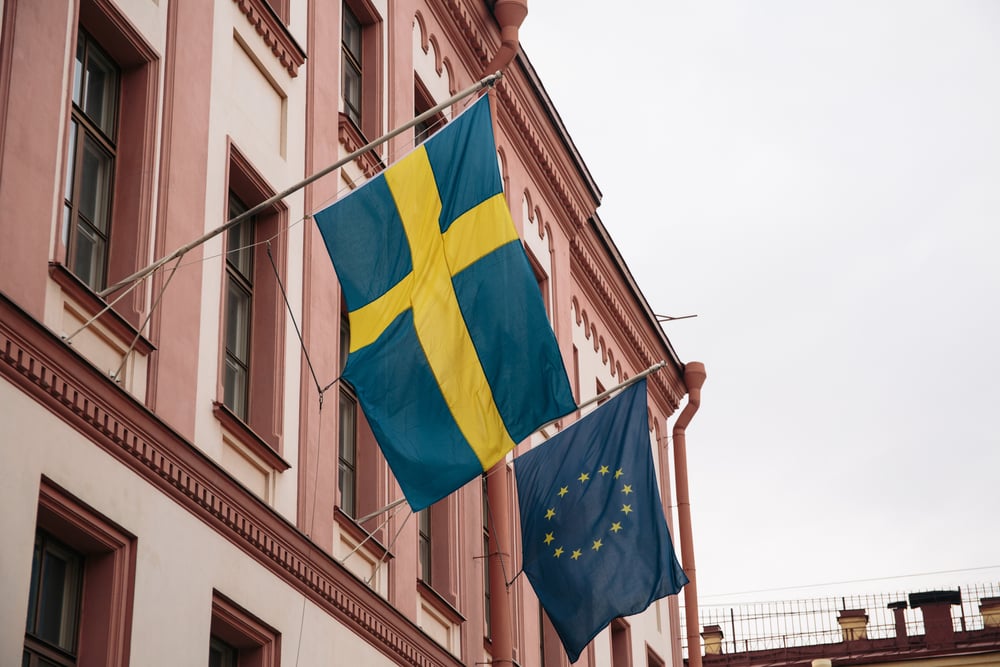 flag of Sweden and another of the EU hang outside a building