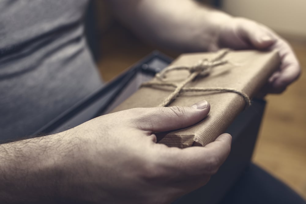 male hands holding suspicious package wrapped in brown paper