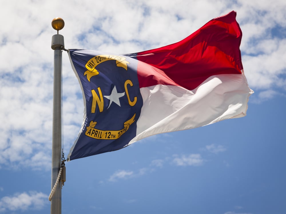 flag of North Carolina against a blue sky and clouds backdrop