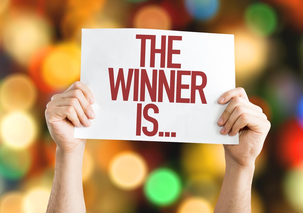 Pair of hands hold up card with the words "the winner is"