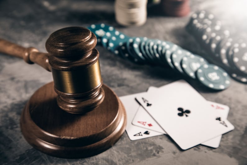 Judge's gavel next to playing cards and poker chips